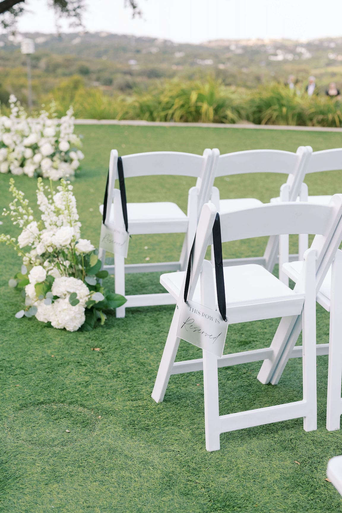 Elegant outdoor ceremony at Omni Barton Creek with white floral arrangements and Hill Country views