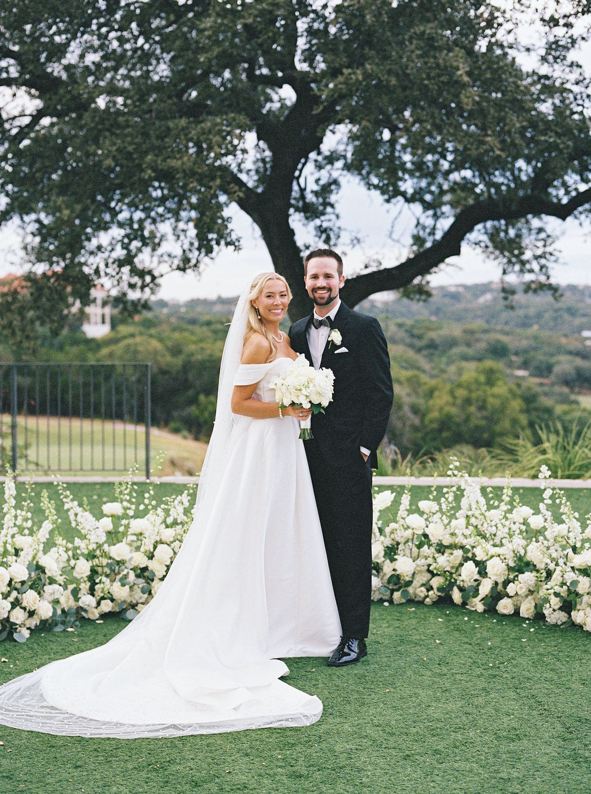 Elegant outdoor ceremony at Omni Barton Creek with white floral arrangements and Hill Country views