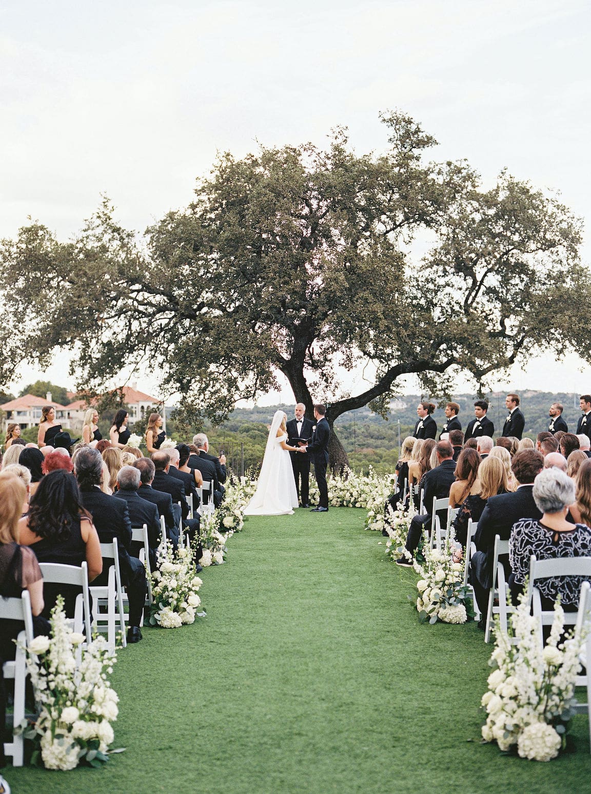 Elegant outdoor ceremony at Omni Barton Creek with white floral arrangements and Hill Country views