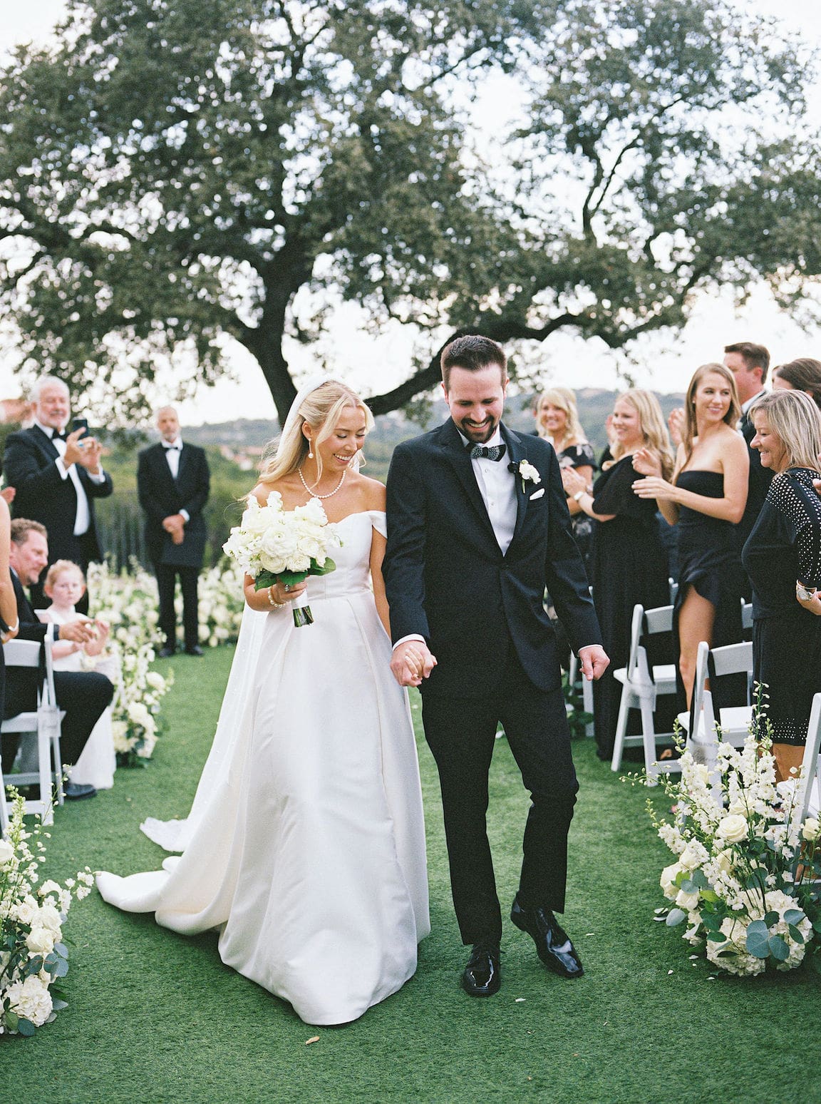 Elegant outdoor ceremony at Omni Barton Creek with white floral arrangements and Hill Country views