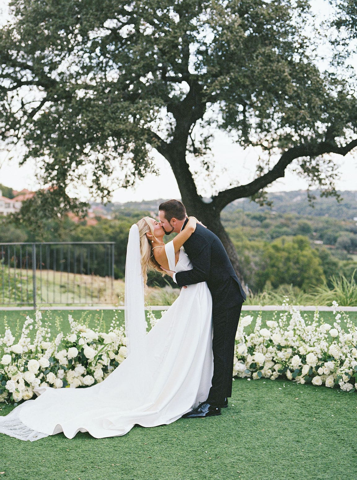 Elegant outdoor ceremony at Omni Barton Creek with white floral arrangements and Hill Country views