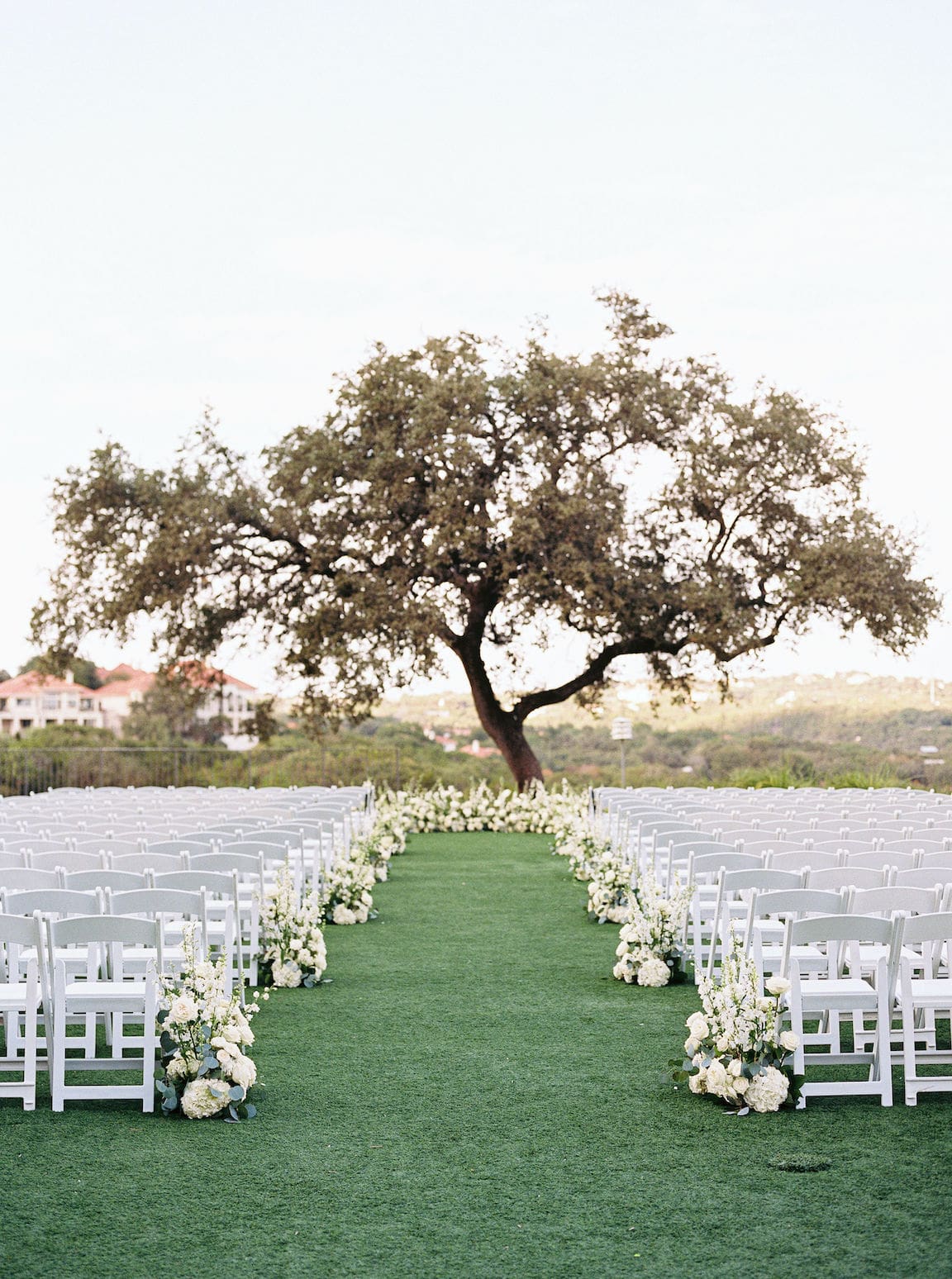 Elegant outdoor ceremony at Omni Barton Creek with white floral arrangements and Hill Country views