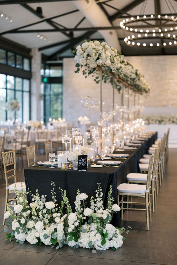 Lush black tie wedding reception at Omni Barton Creek with classic white florals and candlelit tables