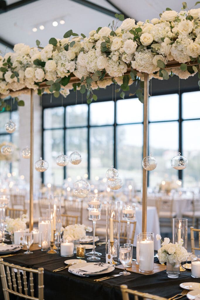 Lush black tie wedding reception at Omni Barton Creek with classic white florals and candlelit tables