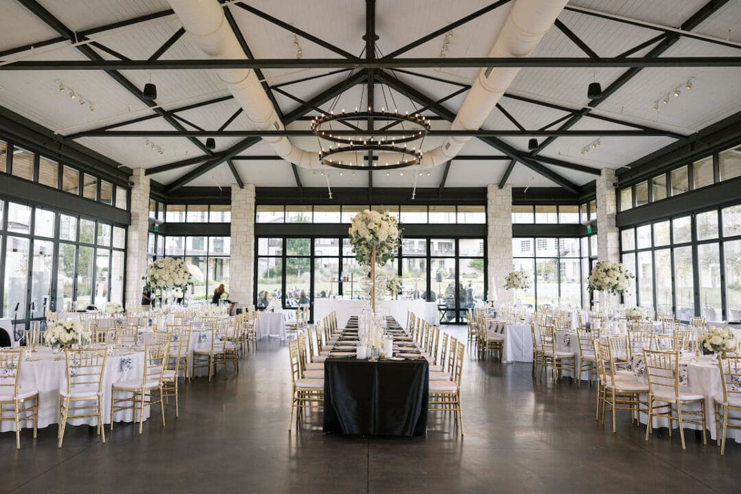 Lush black tie wedding reception at Omni Barton Creek with classic white florals and candlelit tables